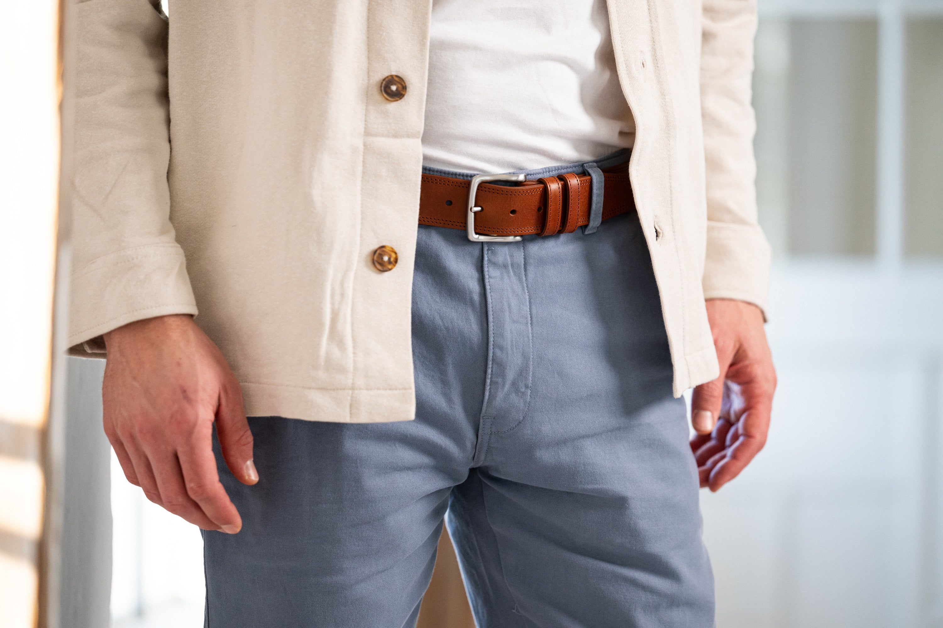 Mann in hellblauer Chino mit 4cm breitem Gürtel in coganc mit doppelter Ziernaht und silberner Schnalle