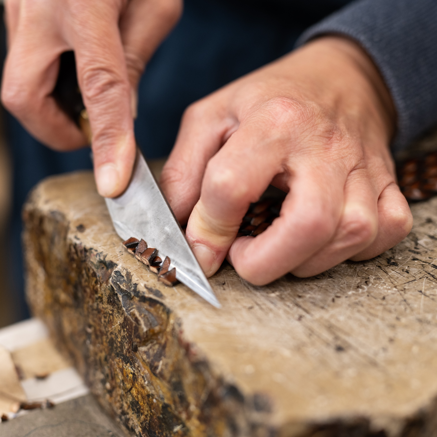 Ein Flechtledergürtel in Braun wird mit einem Messer gekürzt