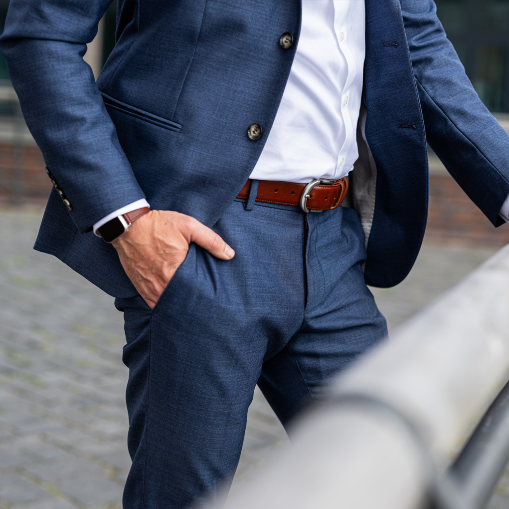 Mann im blauen Anzug mit hellbraunem, klassisch bombierten Ledergürtel